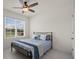 Bedroom featuring light floors, neutral walls, a ceiling fan, and a window with a view of trees and a house at 2686 Neverland Dr, New Smyrna Beach, FL 32168