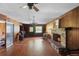 Cozy living room featuring wood paneling, a brick fireplace, hardwood floors, and a vintage style ceiling fan at 2919 Griffin Rd, Leesburg, FL 34748