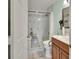 Bathroom with white marble tile, mosaic detail, dark wood cabinets, white toilet with safety handles, and shower seat at 2937 Garret St, Deltona, FL 32738