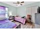 Bedroom with light green walls, wood-look floors, ceiling fan, and two twin beds with colorful bedding at 2937 Garret St, Deltona, FL 32738
