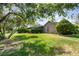 Green backyard with a large shady tree, home's brick exterior and screened in back porch at 3 Whipper In Cir, Ormond Beach, FL 32174