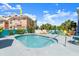 Inviting community pool surrounded by colorful lounge chairs and lush tropical landscaping on a sunny day at 3000 Ocean Shore Blvd # 6, Ormond Beach, FL 32176