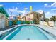 Community pool surrounded by colorful lounge chairs and lush tropical landscaping under a blue sky at 3000 Ocean Shore Blvd # 6, Ormond Beach, FL 32176