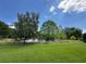 Picturesque backyard view with lush green grass, mature trees, and a tranquil pond at 319 E Victoria Trails Blvd, Deland, FL 32724