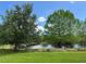 Scenic backyard featuring mature trees, a tranquil pond, and lush green grass under a sunny sky at 319 E Victoria Trails Blvd, Deland, FL 32724