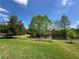 Scenic backyard view featuring lush green lawn, mature trees, and a serene pond under a bright blue sky at 319 E Victoria Trails Blvd, Deland, FL 32724