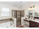 Bright bathroom featuring a soaking tub, tiled shower, and double sink vanity with dark wood cabinets at 319 E Victoria Trails Blvd, Deland, FL 32724