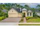 Charming yellow home featuring a three-car garage, landscaped front yard, and inviting entryway at 341 Chelsea Place Ave, Ormond Beach, FL 32174