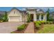 Inviting yellow home boasting manicured landscaping, a brick driveway, and a charming front porch at 341 Chelsea Place Ave, Ormond Beach, FL 32174