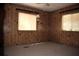 A bedroom featuring wood-paneled walls, two windows, and gray carpet creates a cozy atmosphere at 34416 Oak Ave, Leesburg, FL 34788