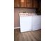 A laundry room featuring a washer and dryer, with light pink walls and wood cabinets at 34416 Oak Ave, Leesburg, FL 34788