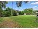 Expansive backyard featuring lush green grass, mature trees, and a storage shed, all within a fenced perimeter at 411 Columbus Ave, Orange City, FL 32763