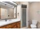 Well-lit bathroom features a vanity, large mirror, and shower with glass doors, as well as a toilet at 411 Columbus Ave, Orange City, FL 32763