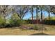 Lush backyard featuring mature trees and manicured hedges, creating a private outdoor space at 421 Holly Fern Trl, Deland, FL 32720