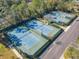 Aerial view of community tennis courts, showcasing the playing surfaces, fencing, and surrounding landscape at 425 Wedgeworth Ln, Deland, FL 32724