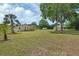 Spacious backyard with a well-maintained lawn, mature trees, palm trees, and a charming home with a wooden deck at 430 S Woodward Ave, Deland, FL 32720