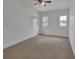 A spacious bedroom featuring neutral carpet, a ceiling fan, and bright natural light from the window at 430 S Woodward Ave, Deland, FL 32720