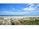 A scenic view of a sandy beach with clear blue water and a partly cloudy sky, showing a tranquil coastal setting at 4670 Links Village Dr # B102, Ponce Inlet, FL 32127