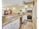 Well-lit kitchen with granite countertops, stainless steel appliances, and breakfast bar overlooking living area at 4670 Links Village Dr # B102, Ponce Inlet, FL 32127