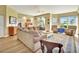 A living room area with a brown sectional sofa and two upholstered chairs on a colorful rug, with light streaming through the windows at 4670 Links Village Dr # B102, Ponce Inlet, FL 32127