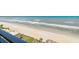 Expansive beach view, showing ocean waves, beach access, and relaxing beachside seating with yellow umbrellas at 5207 S Atlantic Ave # 723, New Smyrna Beach, FL 32169