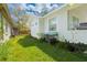 Exterior side of the home showcasing green yard and foliage with trash cans and bins near the house at 5261 3Rd St, Orlando, FL 32810