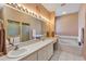 Bright bathroom featuring double sinks, large mirror with vanity lighting, soaking tub, and shower stall at 5305 Indian Ocean Loop, Tavares, FL 32778