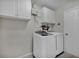 Well-lit laundry room with white washer and dryer, wall-mounted cabinets, and a convenient shelving unit at 5305 Indian Ocean Loop, Tavares, FL 32778