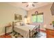 Well-lit bedroom featuring a metal-framed bed, ceiling fan, and window with natural light and neutral decor at 6078 Tivoli Gardens Blvd, Orlando, FL 32829