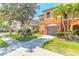 Charming townhome showcasing lush landscaping, a two-car garage, and a welcoming entryway with colorful accents at 6078 Tivoli Gardens Blvd, Orlando, FL 32829