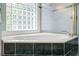 Close-up of a bathtub surrounded by dark green tile and a glass block window at 6111 Oxbow Bend Ln, Port Orange, FL 32128