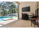 Open-air patio with a grill and television, leading to a screened pool area for outdoor enjoyment at 6111 Oxbow Bend Ln, Port Orange, FL 32128