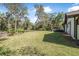Expansive backyard featuring a lush lawn, mature trees, and a patio set with red umbrella at 6247 Palomino Cir, Port Orange, FL 32127