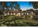Charming single-story home featuring stone accents, a well-manicured lawn, and mature trees under a beautiful evening sky at 6247 Palomino Cir, Port Orange, FL 32127