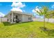Well-maintained backyard with green lawn, white fence, covered patio, and grill for outdoor enjoyment at 7068 Lanier Falls Rd, Deland, FL 32724