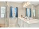Bright bathroom featuring double sinks, a large mirror, and a glass-enclosed shower with a built-in seat at 7068 Lanier Falls Rd, Deland, FL 32724
