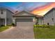 Exterior of a gray home with a well manicured yard, brick driveway at sunset at 7068 Lanier Falls Rd, Deland, FL 32724