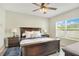 Comfortable bedroom with a large bed, wood furniture, ceiling fan, and a bright window at 7068 Lanier Falls Rd, Deland, FL 32724