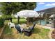 Backyard seating area with umbrella, fire pit, and a view of the screened-in pool at 716 Riviera Bella Dr, Debary, FL 32713
