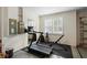 Bright home gym featuring a treadmill, free weights, mirror, and natural light from the shuttered window at 716 Riviera Bella Dr, Debary, FL 32713