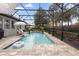 Screened-in pool area featuring lounge chairs, umbrellas, lush landscaping, and clear blue water at 716 Riviera Bella Dr, Debary, FL 32713