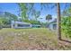 Wide backyard view featuring multiple structures, mature trees, and a verdant lawn at 717 S Ridgewood Ave, Ormond Beach, FL 32174