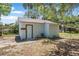 A quaint white shed featuring a simple entry door and minimal landscaping nestled among mature trees at 742 S Martin Luther King Blvd, Daytona Beach, FL 32114