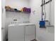 Well-lit laundry room with shelving and decor, includes washer, dryer, and cleaning supplies at 9392 Revere Ave, Leesburg, FL 34788