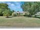 Attractive yellow house with a green lawn, shrubs, and mature trees under a blue sky at 1033 Pearl Tree Rd, Deltona, FL 32725