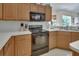 A kitchen featuring wood cabinets, countertops, and black oven range and microwave at 1033 Pearl Tree Rd, Deltona, FL 32725
