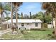 Quaint white home featuring a metal roof, tidy front yard, and mature palm trees at 104 Hester Ave, New Smyrna Beach, FL 32168