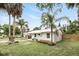 Beautiful white home with carport, metal roof, well-manicured lawn, and mature palm trees at 104 Hester Ave, New Smyrna Beach, FL 32168