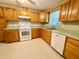 Classic kitchen with wooden cabinets, white appliances including oven and dishwasher, and plenty of countertop space at 111 S Delaware Ave, Deland, FL 32720