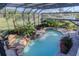 Aerial view of a backyard featuring a pool with a waterfall, a hot tub, and lush, tropical landscaping at 1117 Oxbridge Ln, Ormond Beach, FL 32174